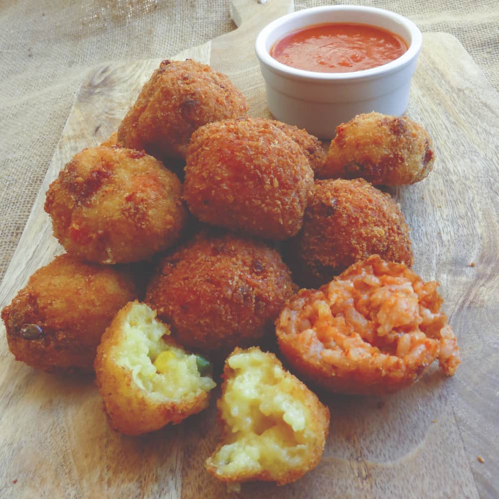 You are looking at a small pile of arancini balls with a saucer of sauce.