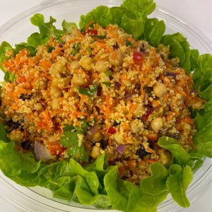 A bowl of coulourful couscous salad with chickpeas, grated carrot and red onion on a bed of lettuce.